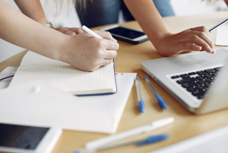 Personas estudiando juntas con ordenador y cuadernos